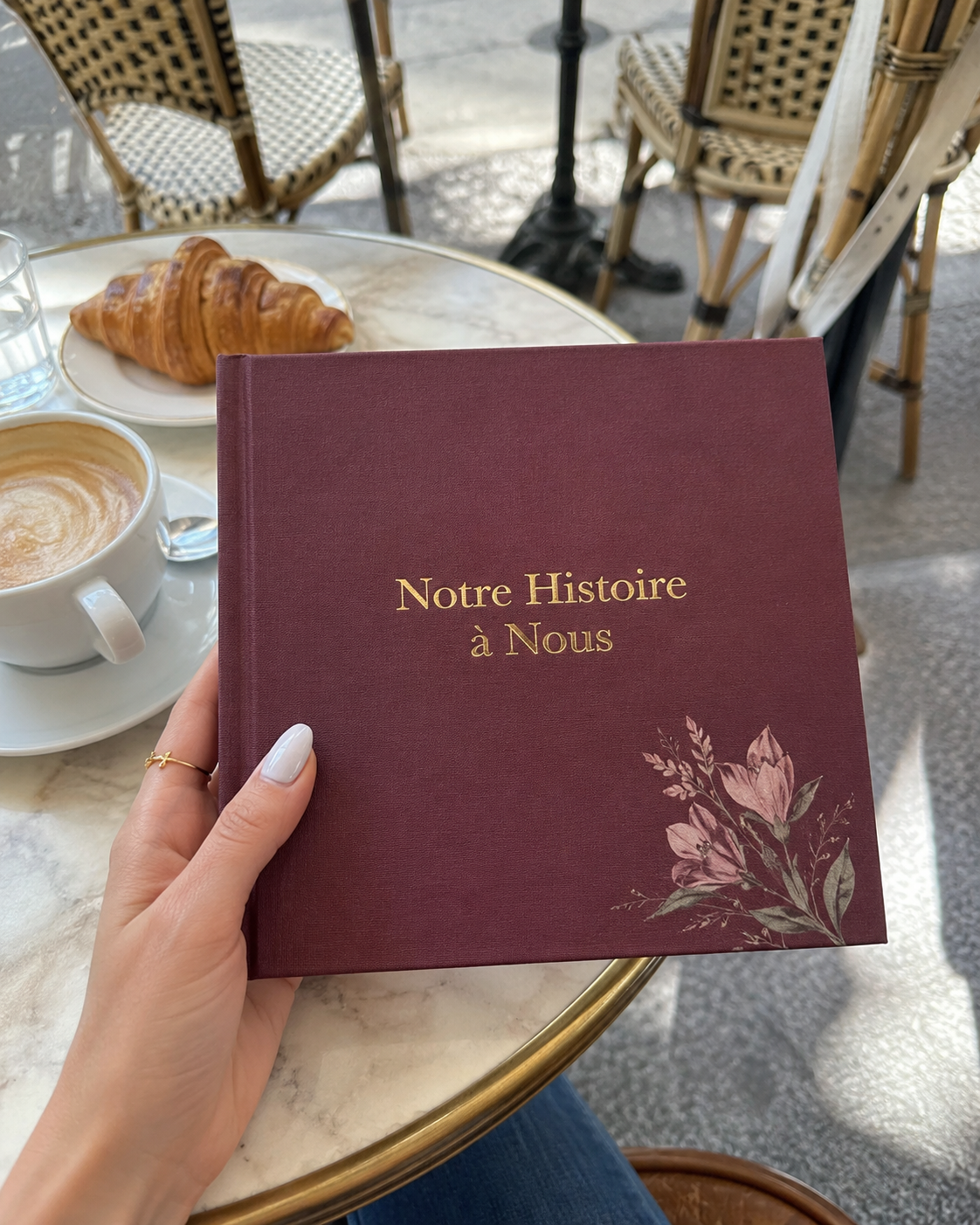 Le livre Notre Histoire tenu à la main dans un café