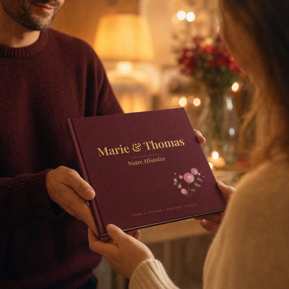 Couple offrant le livre d'amour personnalisé relié bordeaux « Marie & Thomas », ambiance chaleureuse aux bougies